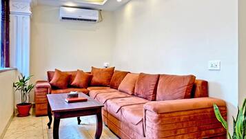 A living room with a large sectional sofa, a wooden coffee table, and a potted plant.