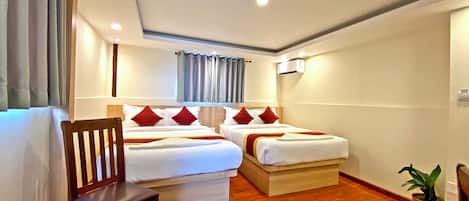 A hotel room with two beds, a wooden chair, a small round table, and a potted plant.