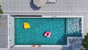 A rectangular swimming pool with clear blue water, surrounded by a tiled deck.