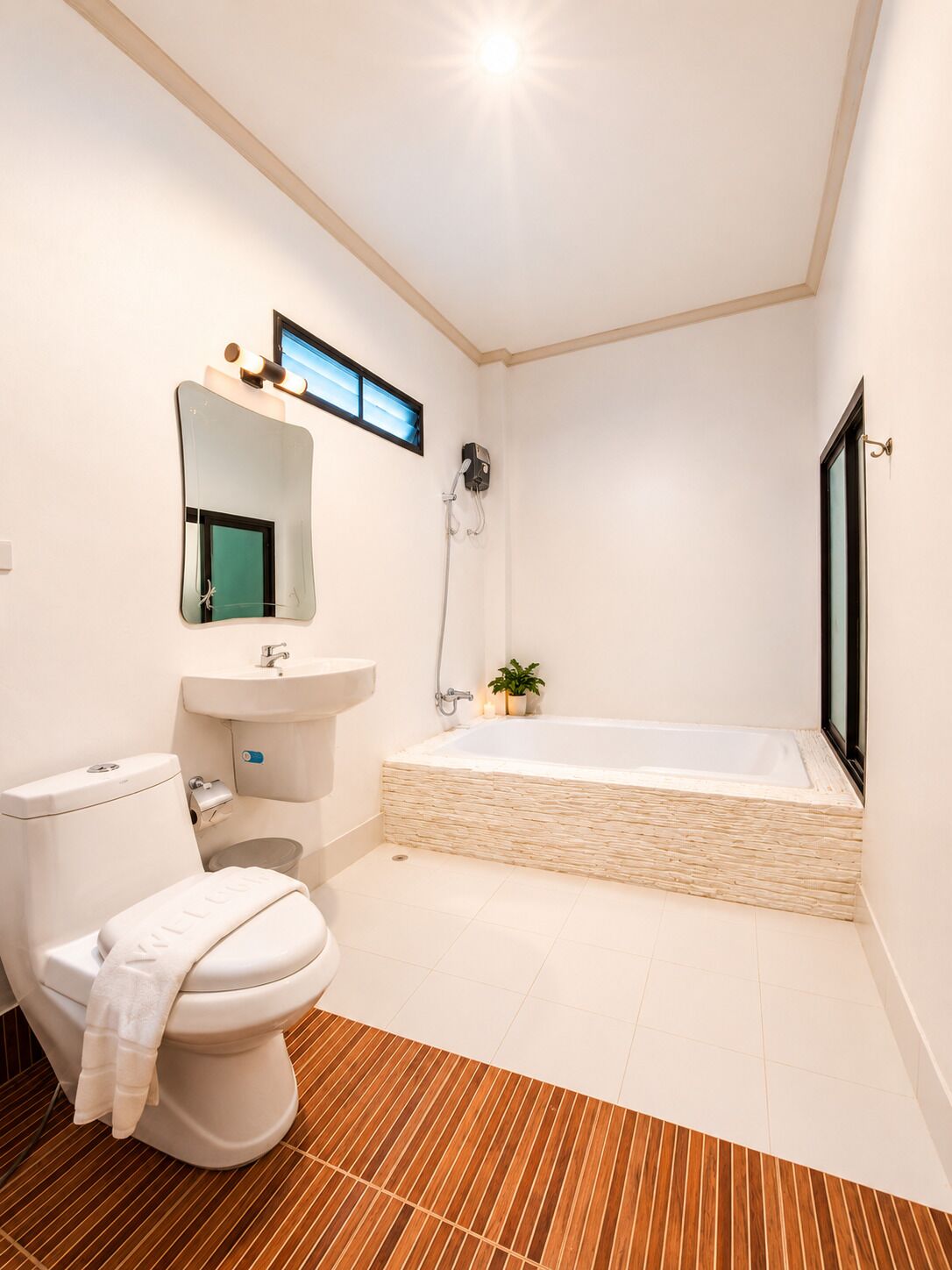 Een moderne badkamer met toilet, wastafel, spiegel en een ruime badkuip.