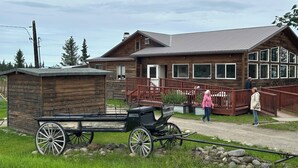 A wooden cabin with a porch and a carriage. - 
Denali Haven: A Cosy Alaskan Retreat near Denali NP (Healy)