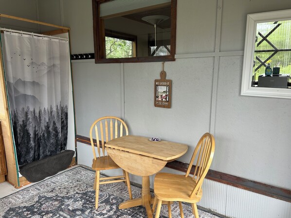 Una habitación con una mesa de madera y dos sillas, un espejo sobre la mesa y una ventana con vistas a la vegetación.