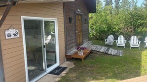 A cabin with a sliding glass door, a wooden deck, and a welcome mat. - 
Denali Haven: A Cosy Alaskan Retreat near Denali NP (Healy)