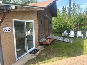 A cabin with a sliding glass door, a wooden deck, and a welcome mat.