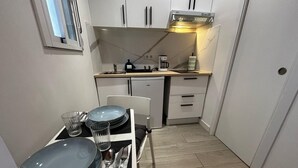 A compact kitchen with white cabinets, a built-in oven, and a small dining area with a table set for two.
