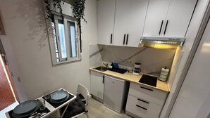 A compact kitchen with a dining area, a built-in oven, a sink, and a small refrigerator.