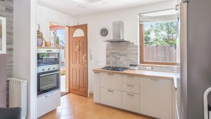 A modern kitchen with white cabinets, a built-in oven, a gas stove, and a stainless steel refrigerator.