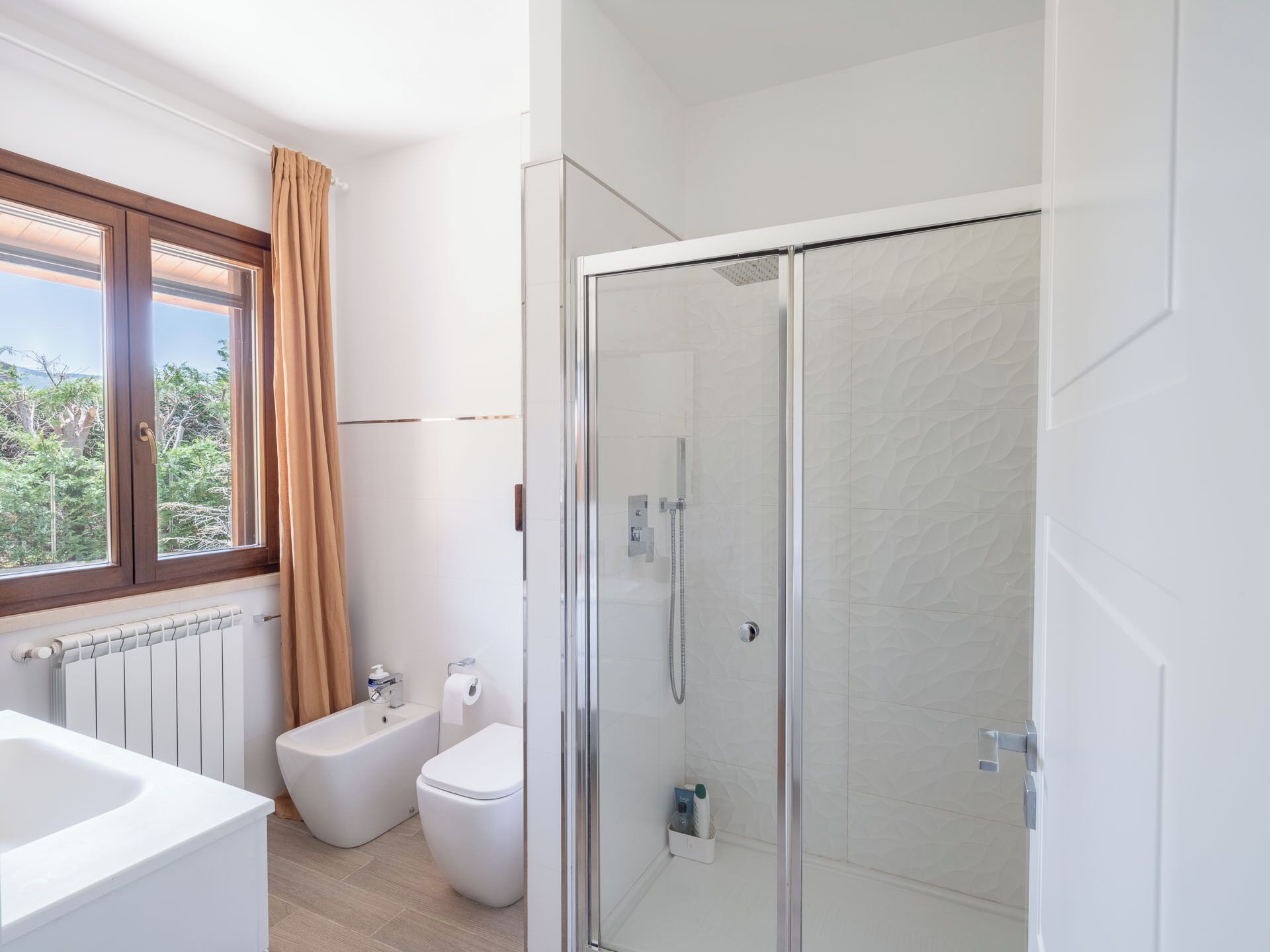 Un baño moderno con ducha envuelta en vidrio, una bañera y un inodoro.