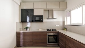 A modern kitchen with a built-in microwave, oven, and wooden cabinetry.