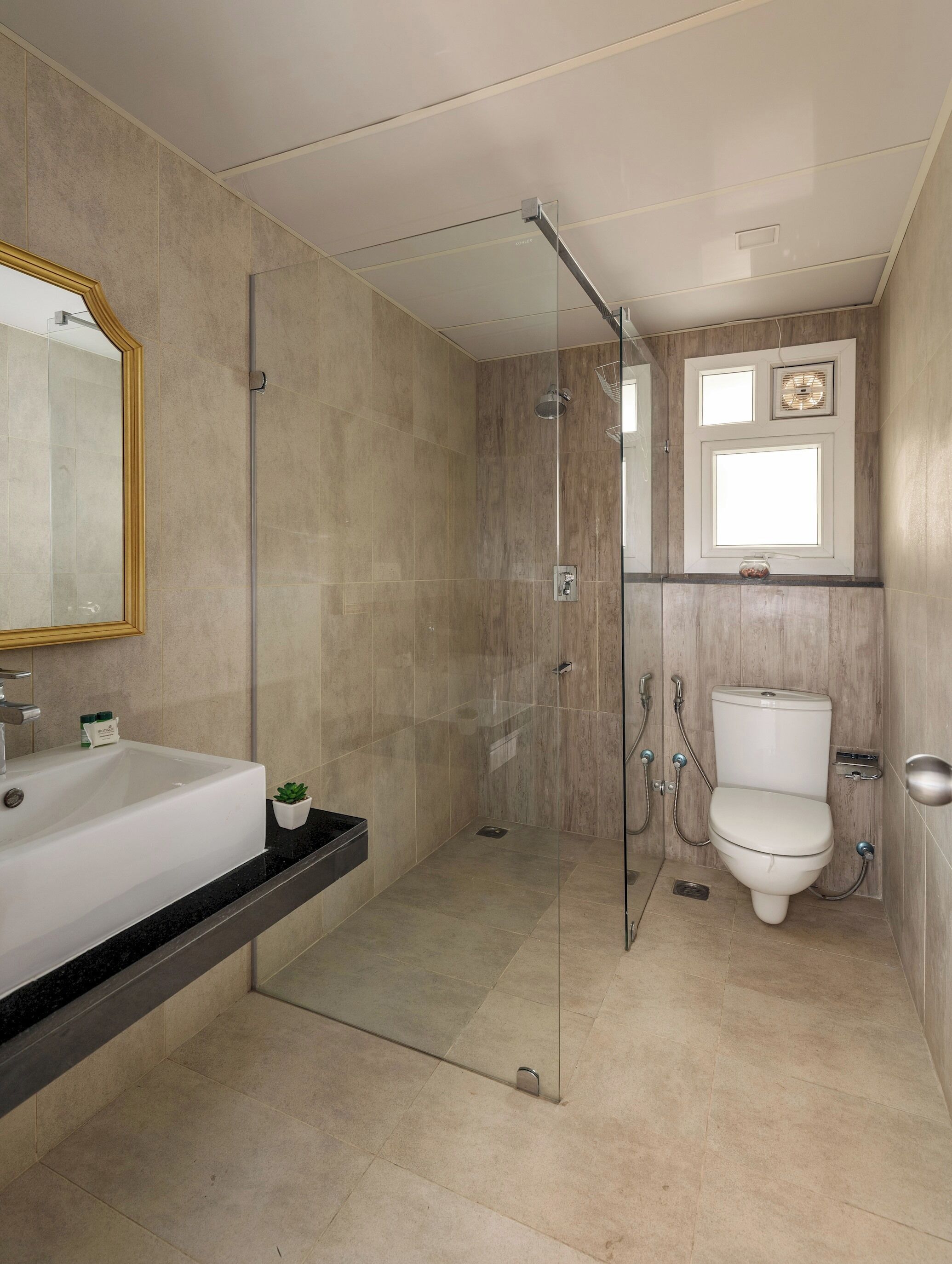 A modern bathroom with a glass shower enclosure, a white sink, and a toilet.