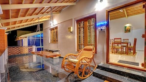A wooden rocking chair on a marble floor, a 'WELCOME' mat, and a view into a dining area with wooden furniture. - Rosedale Farmhouse (Denkanikota)