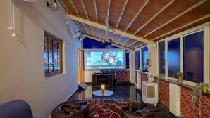 A cozy living area with a large screen, comfortable seating, and a decorative ceiling. - Rosedale Farmhouse (Denkanikota)