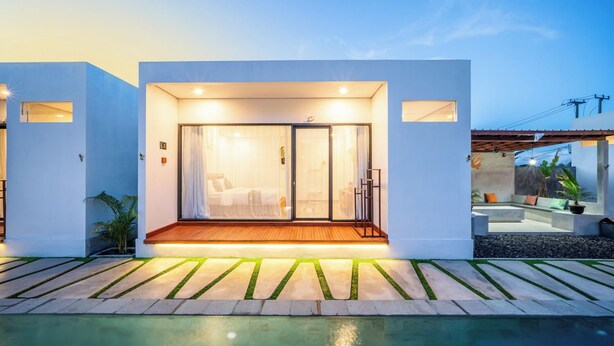 Een modern huis met een glazen deuropening, een houten terras en een zwembad.