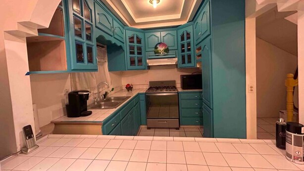 A kitchen with teal cabinets, a stove, and a sink. - Charming 4-bedroom house with WiFi in Playas de Rosarito, secure gated parking (Playas de Rosarito)