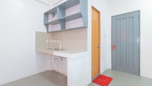 Een kleine keuken met een spoelbak, een houten deur en een grijze deur.