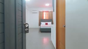 Een hotelkamer met een bed, een deur met een 'Niet Storen'-bordje en een airconditioner aan de muur.