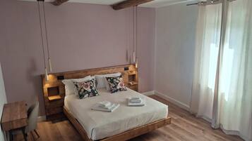A bedroom with a wooden bed, a desk, and a window with curtains.