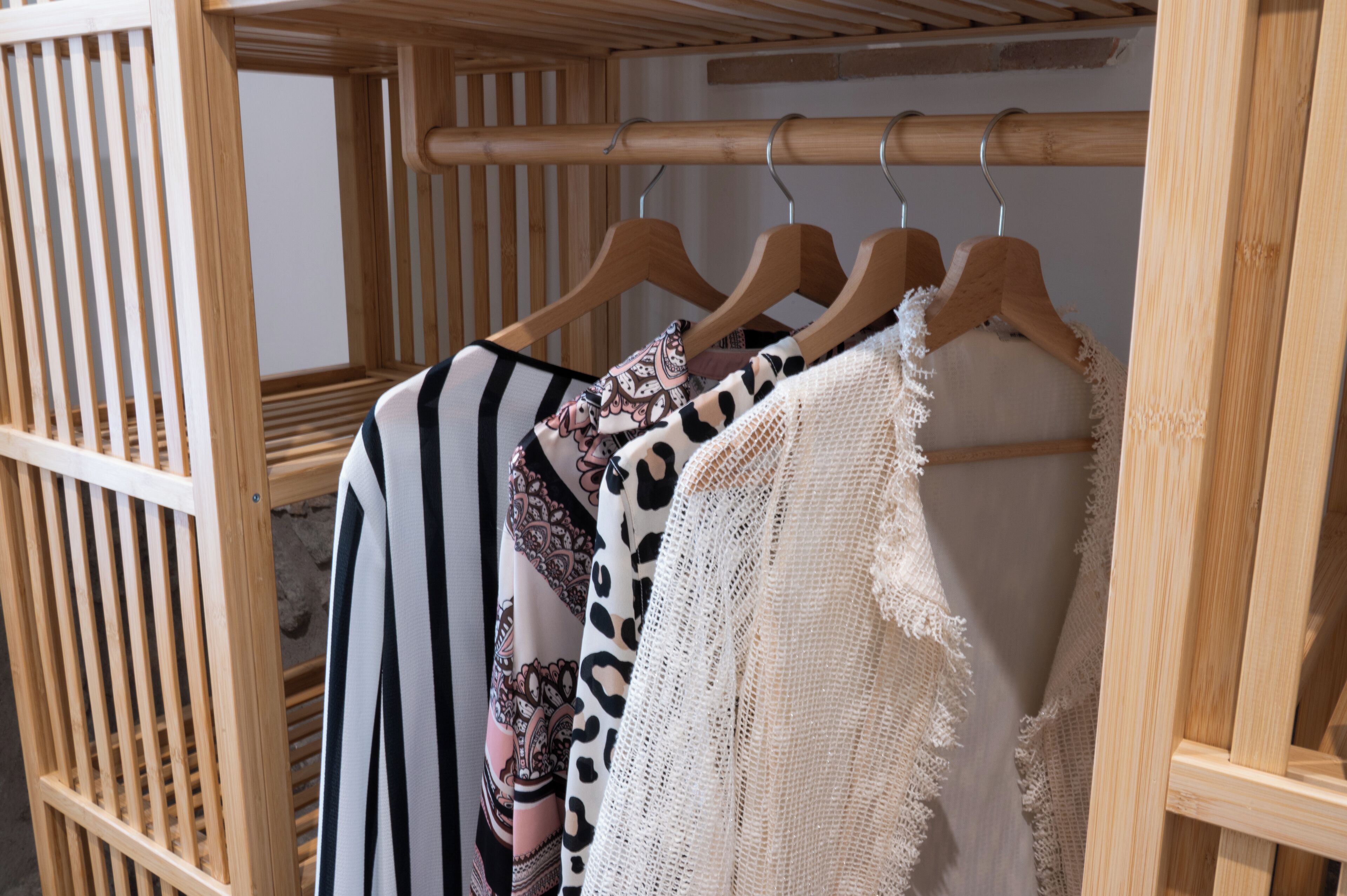 Een houten garderobe met meerdere hangers, elk met een ander kledingstuk.