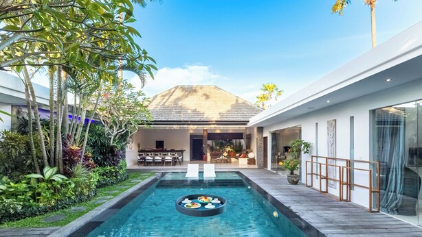 A modern outdoor pool area with a dining setup and lush greenery. - Villa Naema - 4 BR Private Villa (Seminyak)