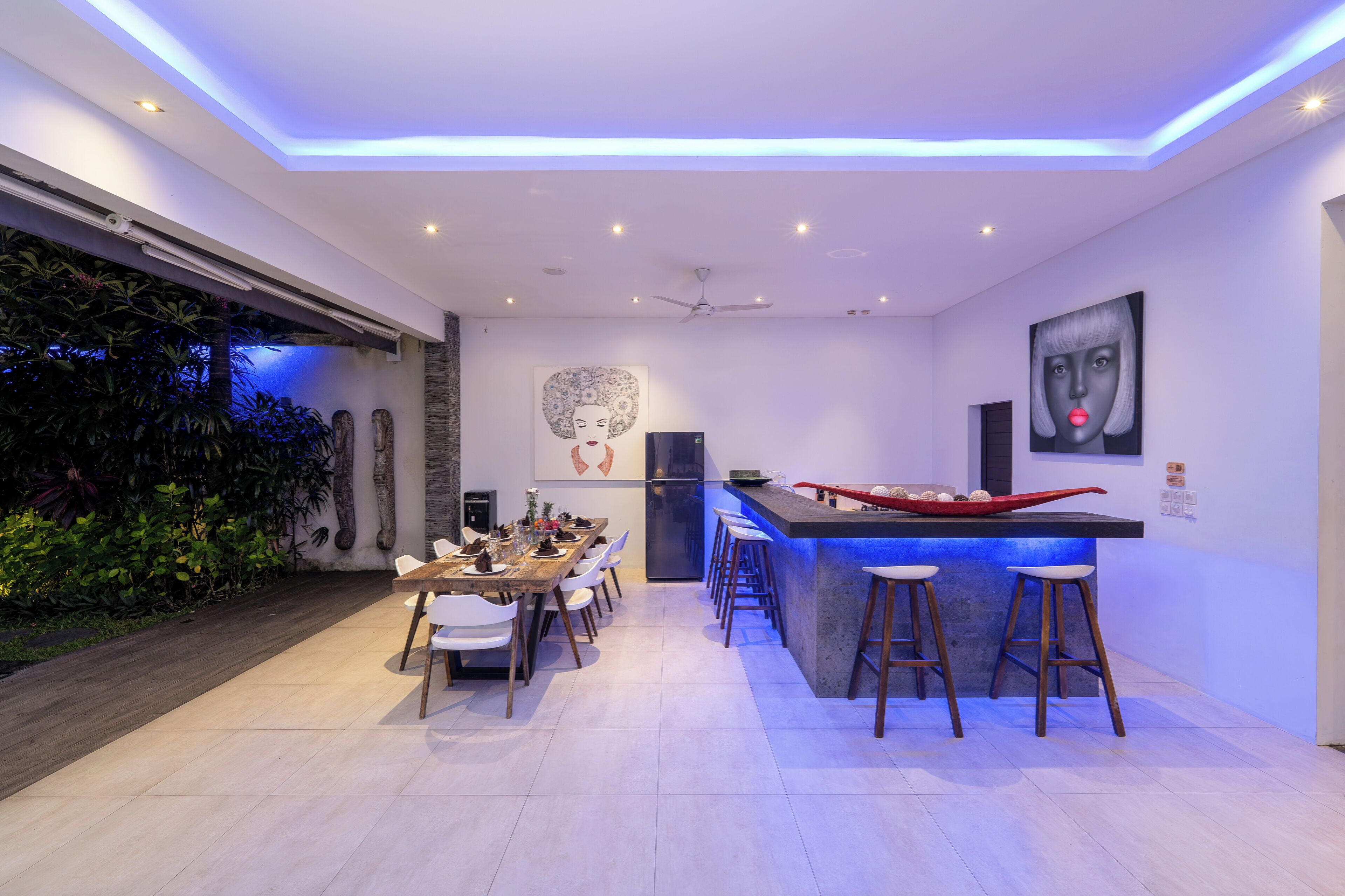 Una cocina moderna con barra, sillas blancas y una mesa de comedor.