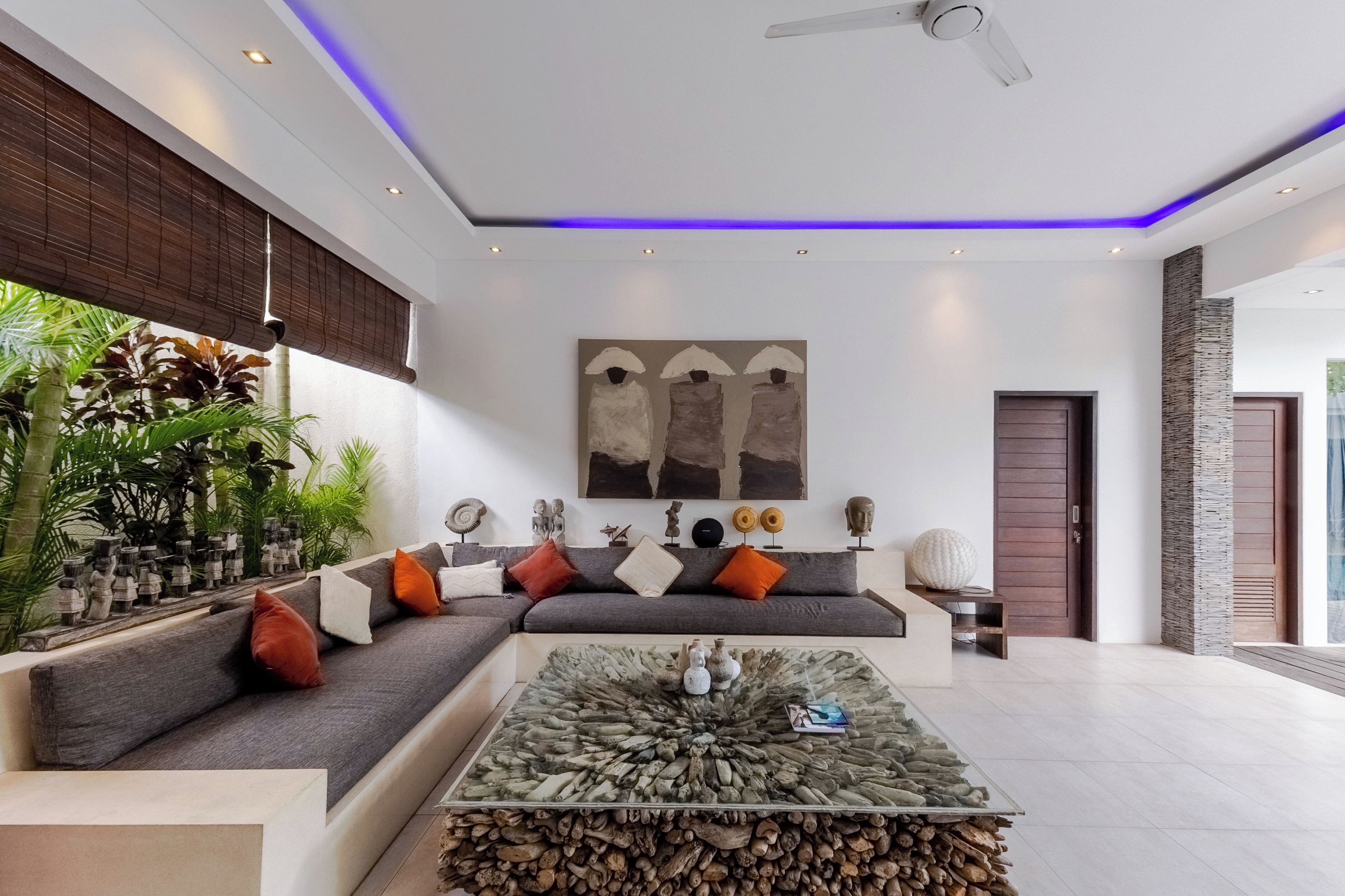 Una sala de estar moderna con un sofá modular, una mesa de centro de vidrio y objetos decorativos.