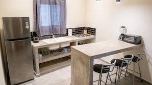 Une cuisine compacte équipée d’un réfrigérateur, d’un évier, d’une cuisinière et de tabourets de bar.