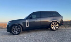 A black SUV parked on a gravel road with a clear sky in the background.
