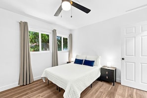 A bedroom with a bed, nightstand, and a ceiling fan.