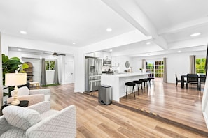 A spacious kitchen with a central island, a dining area with a table and chairs, and a seating area with a sofa and a lamp.