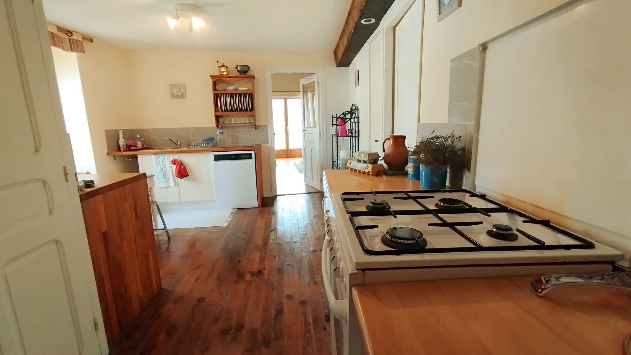 Una cocina con estufa a gas, armarios de madera y una pequeña isla con fregadero.