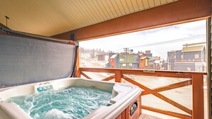 A hot tub on a wooden deck with a view of a town.