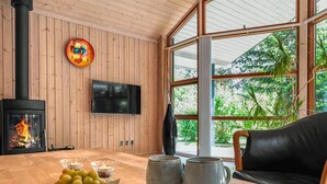 A cozy room with a wooden interior, a fireplace, a television, and a view of greenery outside. - "Rosaline" - 500m from the sea by Interhome (Grenaa)