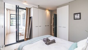A modern bedroom with a large bed, a sliding door to a balcony, and a view of the outside. - Cape Eazi Stayz The Decks (Cape Town)