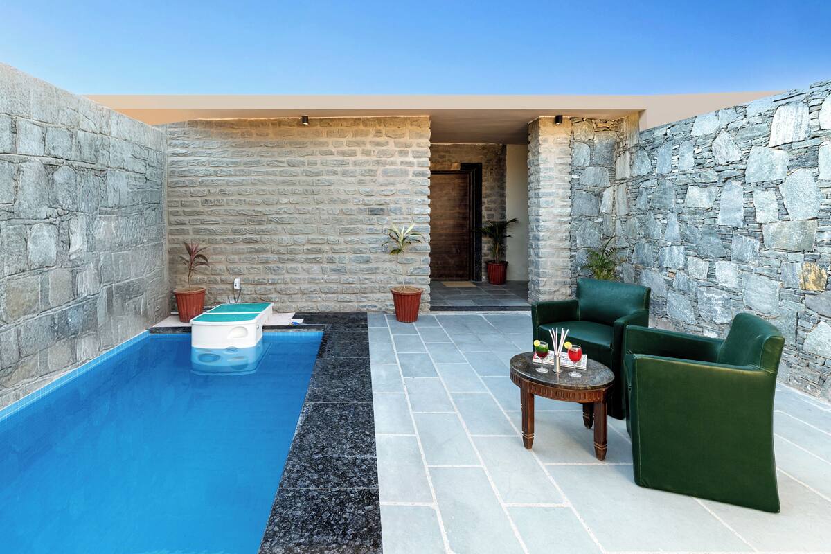 A pool area with stone walls, a small pool, and green seating.
