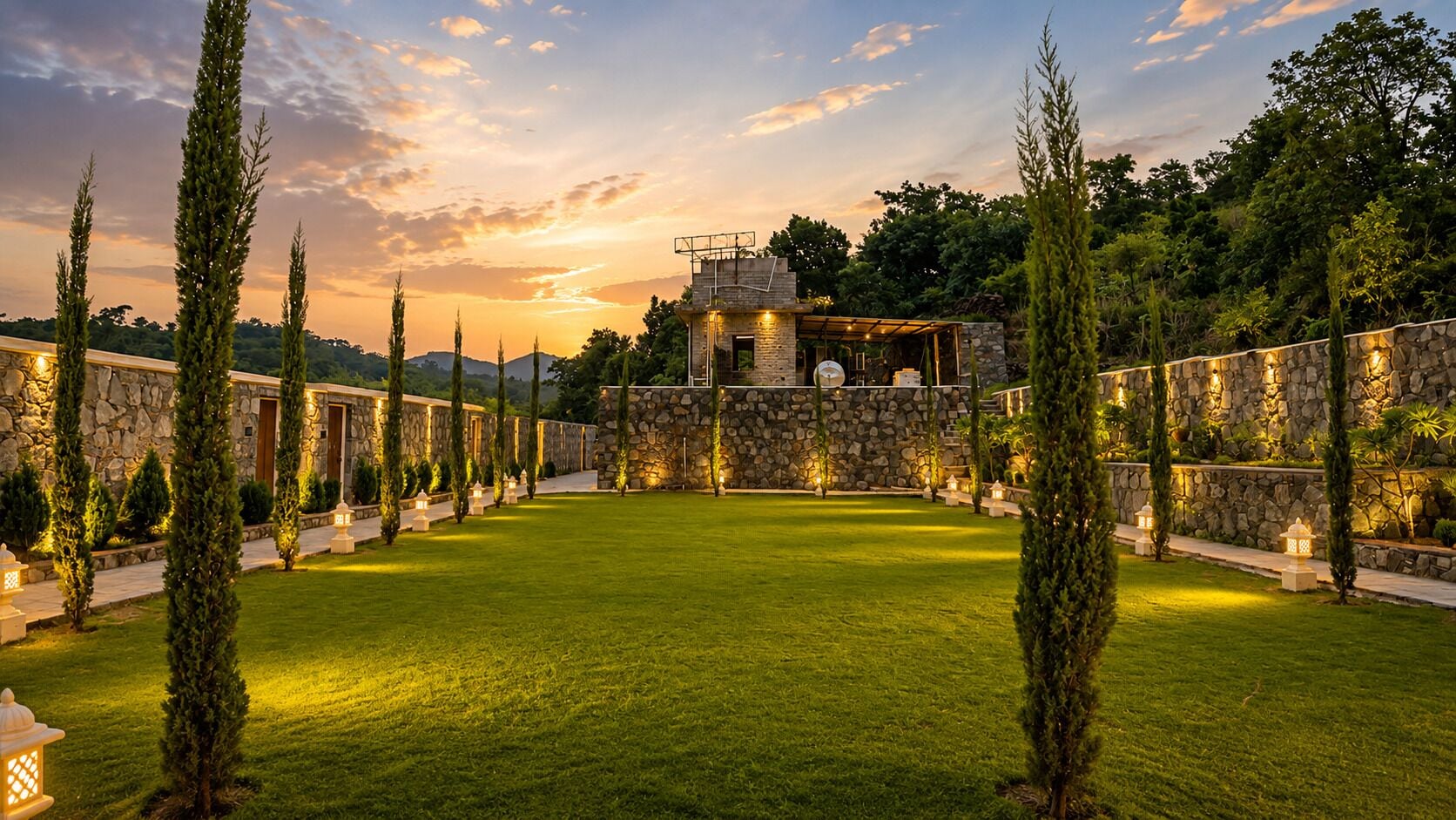A courtyard with a stone wall, a grassy lawn, and a building with a balcony.