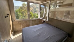 Un dormitorio con cama, ventana y espejo.