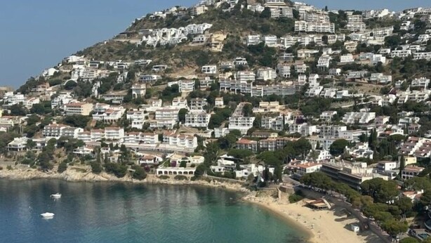 Un pueblo costero con edificios en una ladera con vistas a una playa.
