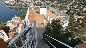 Una escalera conduce a una terraza en la azotea con vistas a un pueblo costero.