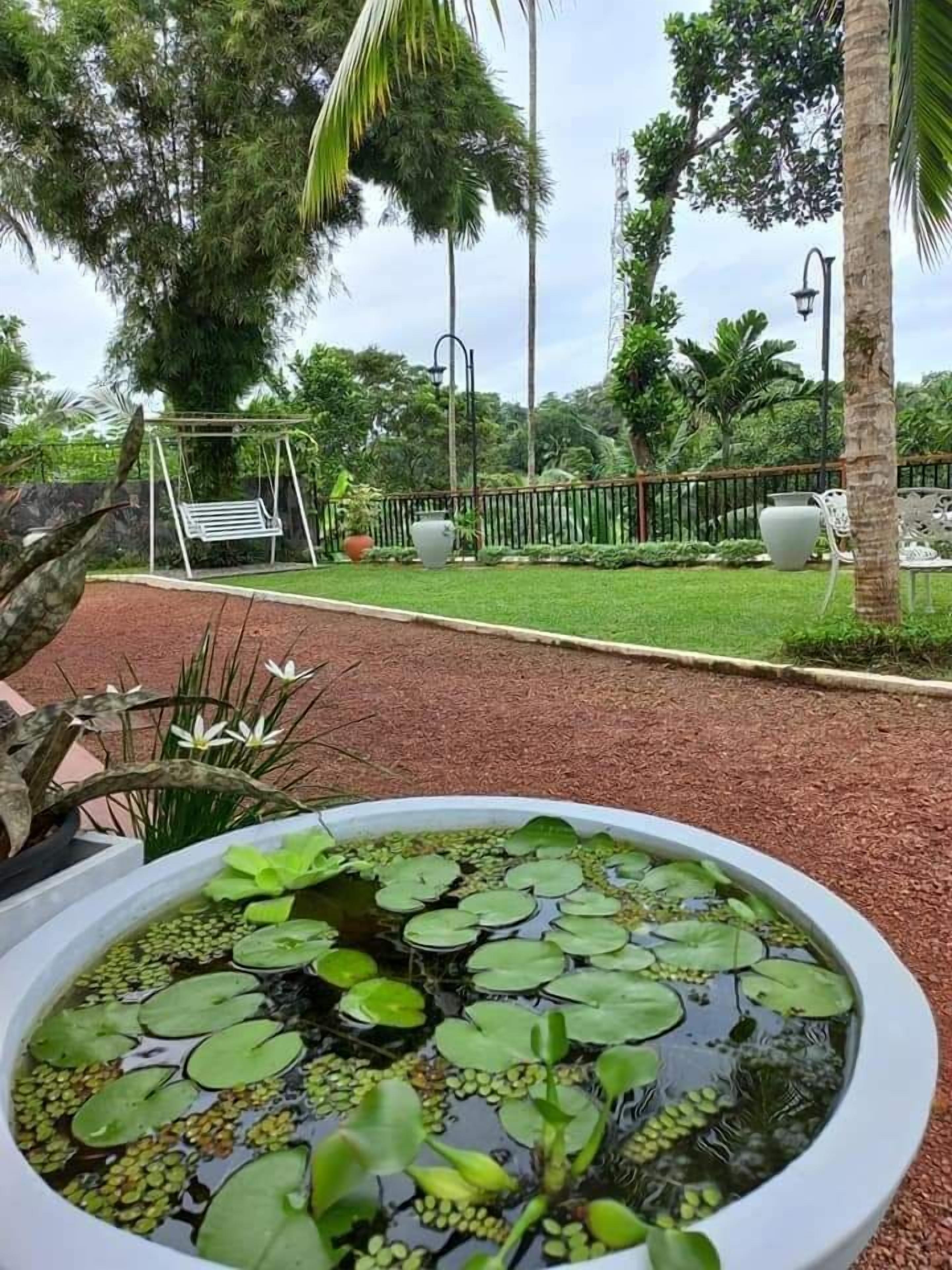Un jardín con un estanque, un columpio y un camino pavimentado.
