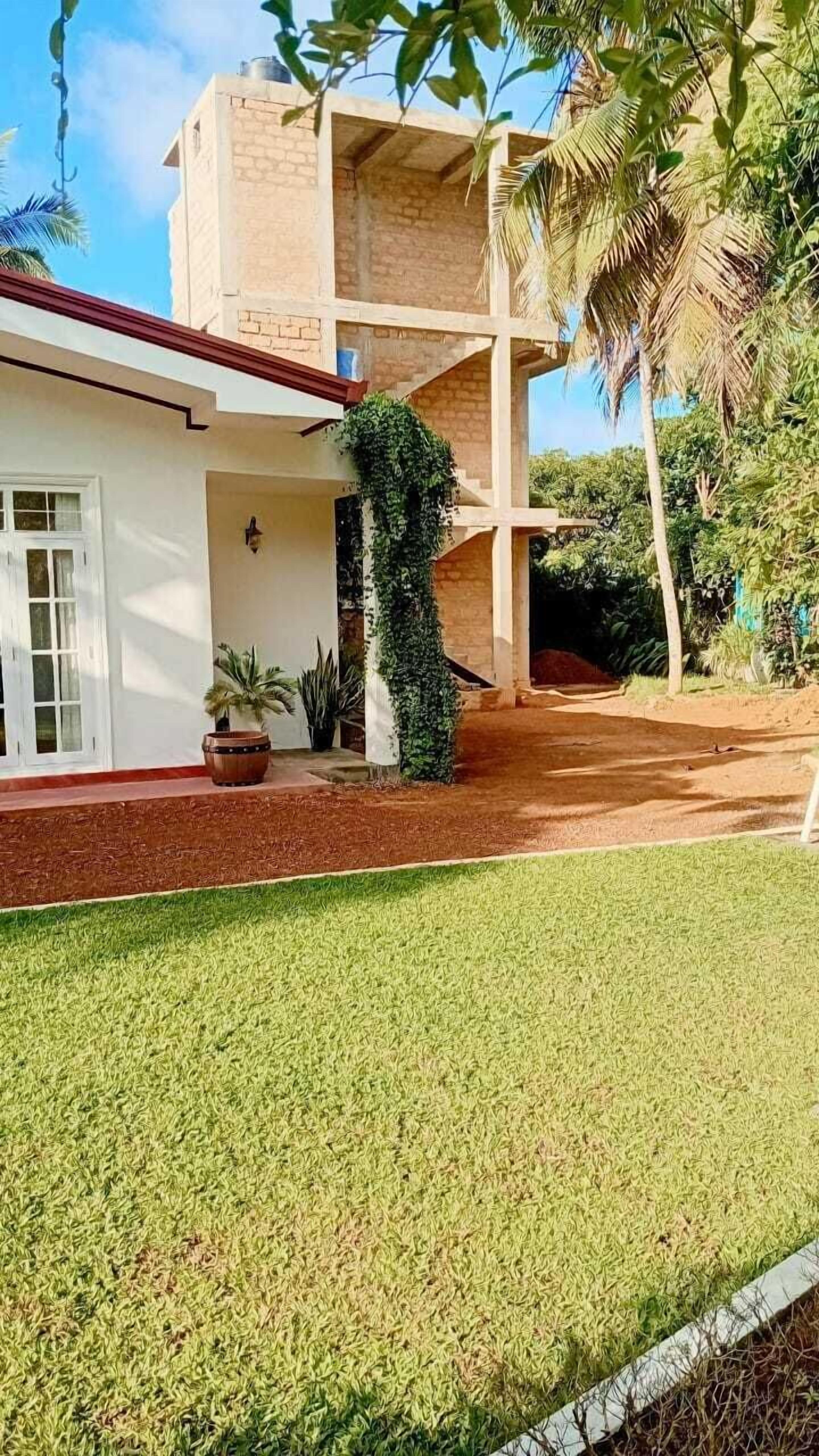 Una casa de dos pisos con techo rojo, paredes blancas y césped cuidado.