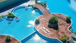 Una gran piscina con múltiples carriles, una isla central y jardines aledaños.