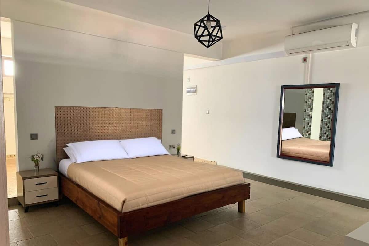 Een moderne slaapkamer met een houten bed, een nachtkastje, een wandlamp en een wandairconditioning.