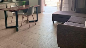 A modern living room with a sofa, a dining table with chairs, and a kitchen area with a stove and cabinets. - THE LIGHT VILLA (Trou d'Eau Douce)