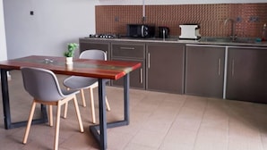 A compact kitchen with a dining area, featuring a modern stove, microwave, and cabinets. - THE LIGHT VILLA (Trou d'Eau Douce)
