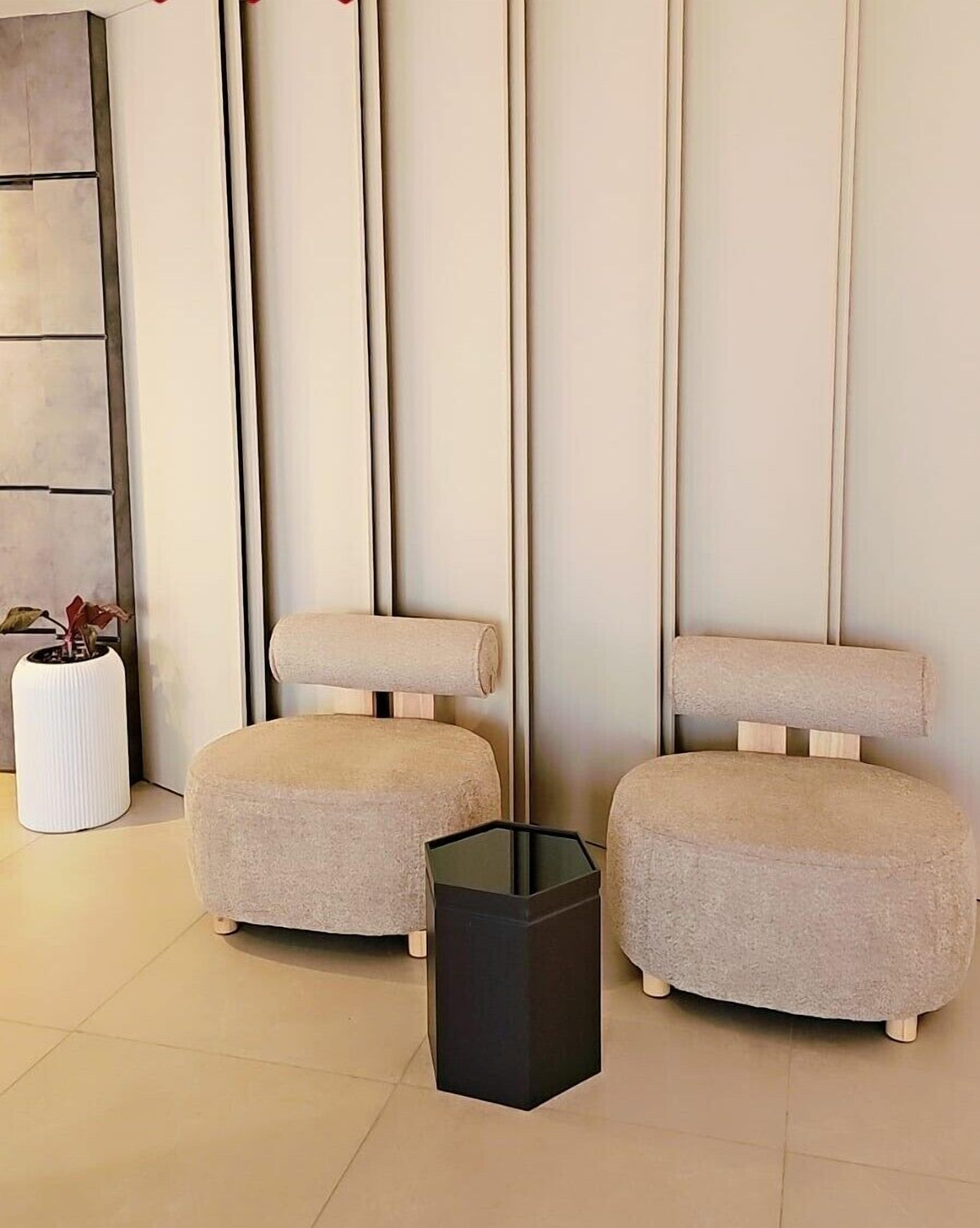 Quarto moderno com dois pufes redondos e uma mesa lateral preta.