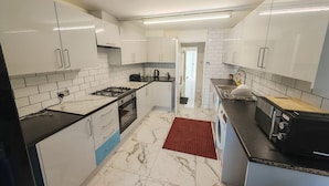 Een moderne keuken met witte kasten, een gasfornuis en een magnetron.