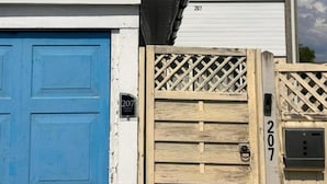 Een gebouw met een blauwe deur en een houten poort, beide met het nummer 207.