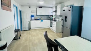 A compact kitchen with white cabinets, a refrigerator, and a dining table with chairs.