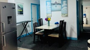 A compact kitchen with a refrigerator, a dining table with chairs, and a small dining area.