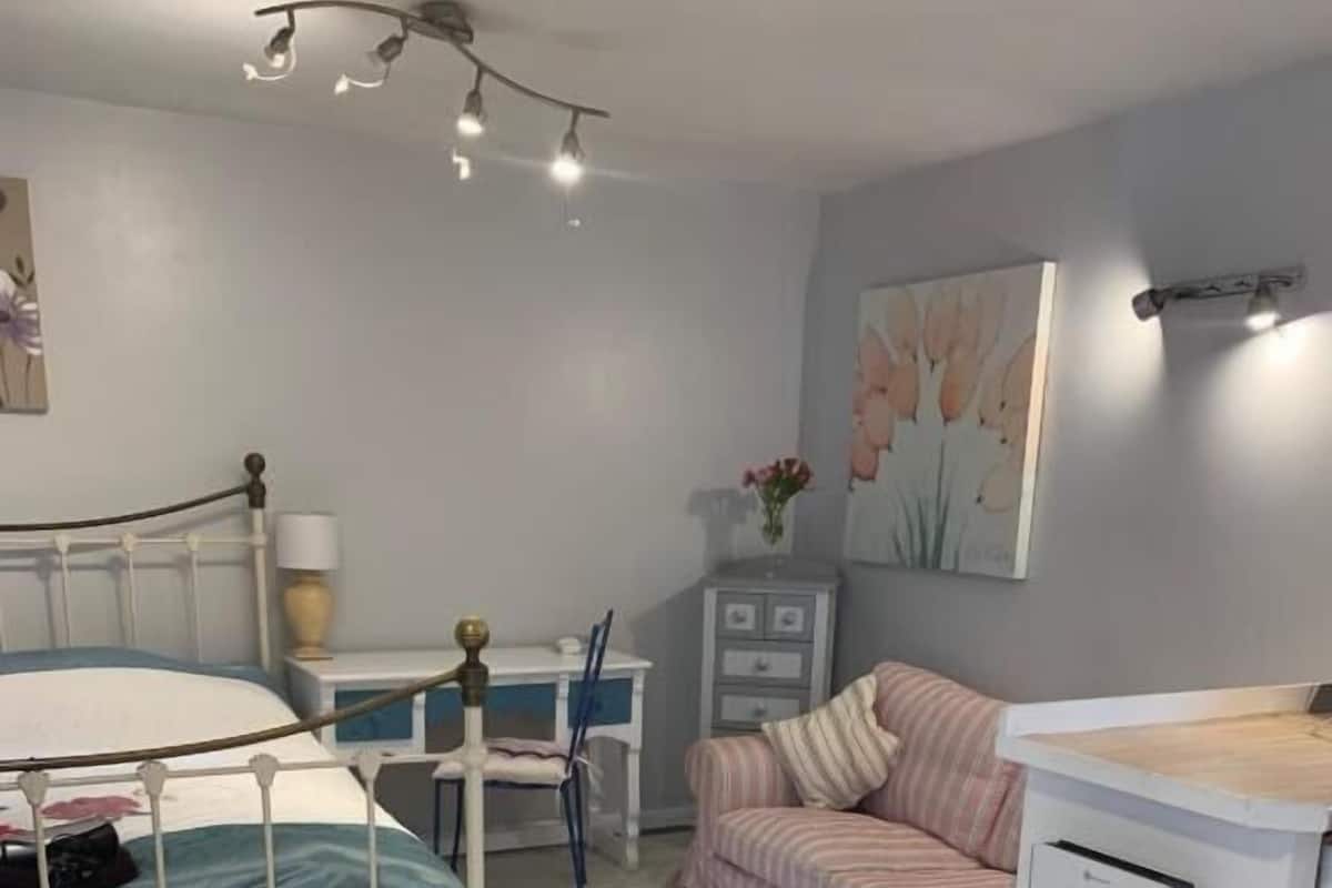 Ein Schlafzimmer mit Bett, Nachttisch, Sessel und Kommode.